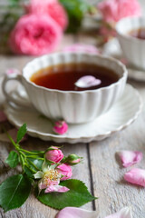 A cup of aromatic tea, a book and a rose on the table.