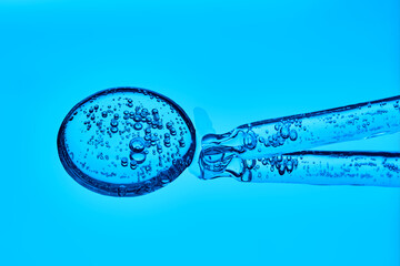 The texture of serum with spicules in a dropper on a blue background.