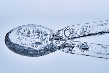 A pipette with hyaluronic serum on a blue background.