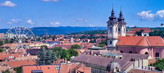 View of the historic center in Eger. Red roofs. Church of Anthony of Padua and the Ferris wheel, castle and mountain in the background. Hungary. Europe