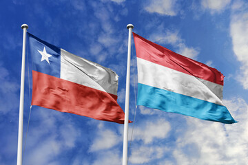 Flags of Chile and Luxembourg Waving Together Under a Bright Blue Sky, Symbolizing International...