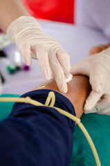 Soft focus on a doctor's hand finding a vein to take a blood sample from his arm for testing in a hospital.