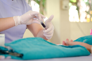 Nurse wearing white medical gloves is drawing blood from patient's arm for examination or PRP procedure. Concept of laboratory research, medicine, analysis.