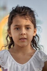 Little girl with wet face standing and looking at camera at sunset time