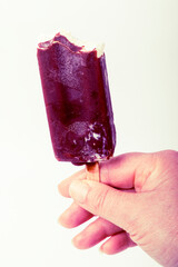 Hand holding a chocolate popsicle showcasing a frozen treat against a white background