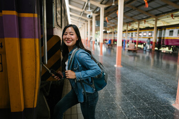 Smiling tourist boarding a train at Hua Lamphong Station in Bangkok, Thailand