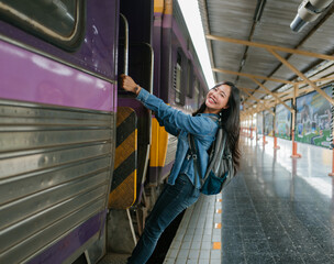 Happy asian tourist getting on the train at the station, beginning her journey