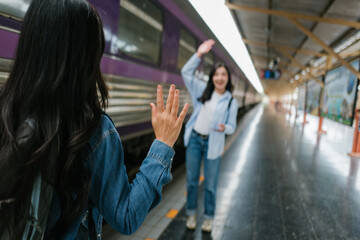 Fototapeta premium Two friends waving goodbye on a train station platform
