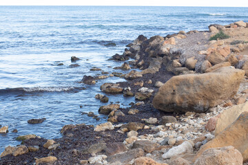 Explore the serene coastal landscape of Spain with rocky shores and calm ocean waves under a clear...