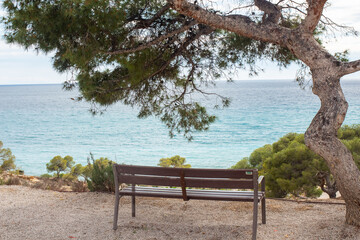 Obraz premium Scenic coastal viewpoint in Spain with a wooden bench overlooking the ocean and tranquil landscape