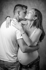 A young couple embraces, with the girl who is at the end of her pregnancy, in black and white