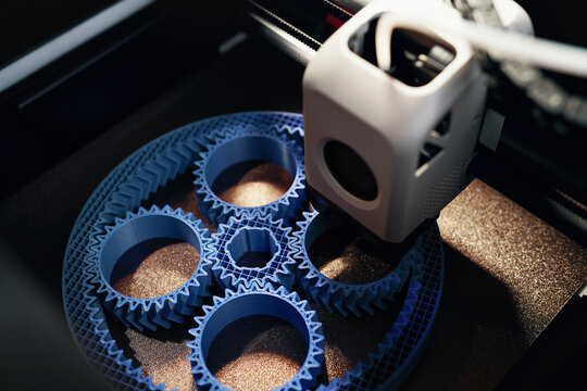 3D printing of a planetary gear set – close-up of FDM printer extruding blue filament for mechanical engineering rapid prototyping and additive manufacturing.