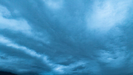 A dramatic view of a lush, forested mountain peak shrouded in thick clouds, capturing the raw...