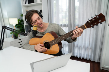 Host channel in smart singer with smiling face, playing guitar along singing, broadcasting on...