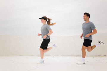 A couple takes pleasure in their morning jog, running side by side along a peaceful coastal walkway...
