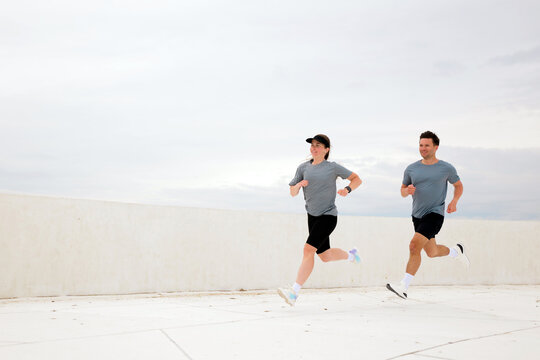Morning joggers embrace the open air on a coastal pathway under a cloudy sky in a vibrant urban setting
