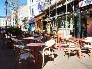 Outdoor café tables on a sunny day Empty chairs and tables bask in Sunday's morning light, waiting...