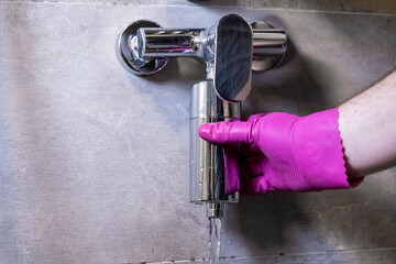 Person in pink glove activates a chrome shower water filter, ensuring clean bathing water and...