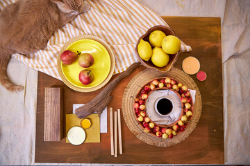 Top view flat lay of a summer-inspired moodboard and color palette arranged on a rustic wooden surface. The scene includes vibrant yellow plates, fresh lemons, ripe cherries, fabric swatches, 