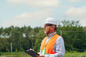 Fototapeta premium Male forest inspector studies the condition of trees in a forest. The work of an ecologist. Carrying out environmental monitoring. Engineering work project.