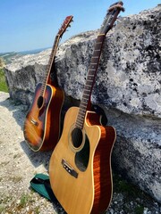two guitars stood near a rock in nature
