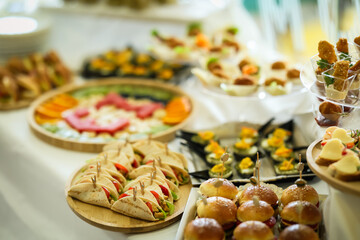 Beautifully arranged catering table with assorted finger foods, fruit platters, mini sandwiches, and desserts, perfect for weddings, receptions, and upscale events.
