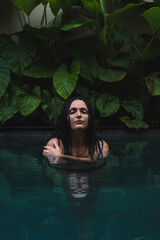 A woman with braids enjoying in a pool, surrounded by lush tropical leaves in a serene and intimate moment in Ubud, Bali, Indonesia