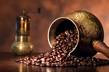 Coffee beans spilling from cezve with traditional copper pattern.
