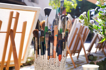 Painting brushes in container outdoors on sunny day.
