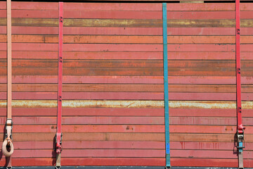Stacked steel plates on a trailer, secured with thick safety ropes, construction site equipment