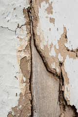Old cracked clay wall. Long deep cracks of a rural house