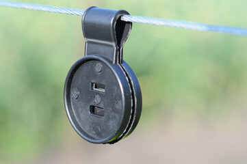 Black clip for attaching shading net to metal cable, closeup