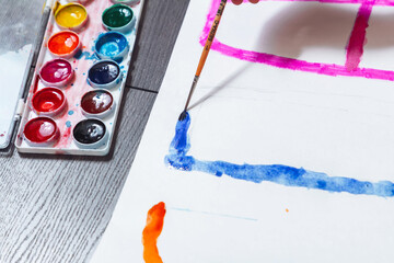 A drop is hanging on a paint brush. Drawing paper lies in a blur.