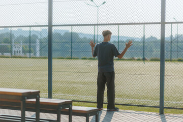 Teen Standing Alone by the Empty Sports Field, Deep in Thought