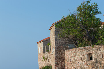 A fragment of the stone medieval fortress of Sveti Stefan island-hotel, on the Adriatic coast,...