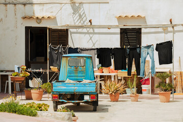 Backyard in Italy with laundry, flowerpots and old rusty blue truck.