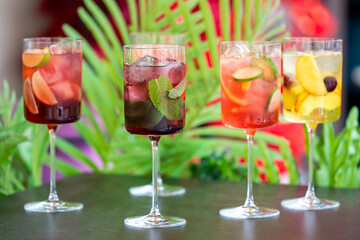 Colorful summer cocktails with ice and fruit garnishes in tall glasses, set against a vibrant tropical background, evoking a fresh and festive atmosphere