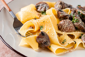 Delicious pappardelle pasta with mushrooms and cream served on a white plate