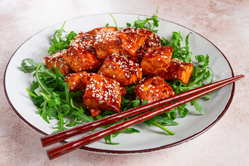 fried salmon slices, teriyaki with sesame seeds, with arugula salad, top view,