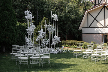 Beautiful outdoor wedding venue featuring a circular arrangement of white chairs and tall floral...