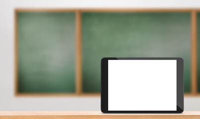 digital tablet with blank screen stands on table against chalkboard background