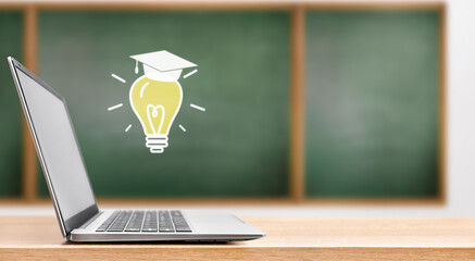 open laptop and hologram in the form of a light bulb in a graduation cap on the background of a school board