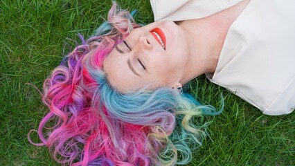 Caucasian woman with colorful hair on green grass.