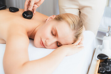 Hot stone massage at spa salon in luxury resort with day light serenity ambient, blissful woman...