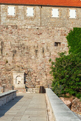 A fragment of the stone medieval fortress of Sveti Stefan island-hotel, on the Adriatic coast, Montenegro. Details. Vertical
