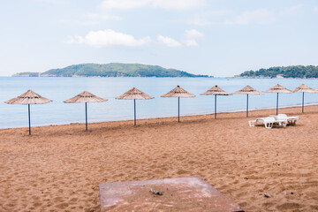 Empty beach with straw umbrellas and lounge chairs. Coastal relaxation, vacation ambiance and summer leisure by the sea.