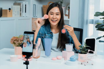 Young beautiful Asian reviewing cosmetic makeup brush cheek testing collection with pastel color,...