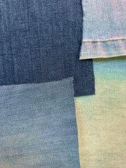 Pieces of material are arranged in attractive fashion as patchwork. The pieces are flat, ironed, clean and cut. Shapes are irregular and colors are muted tones of blue, yellow, tan other.