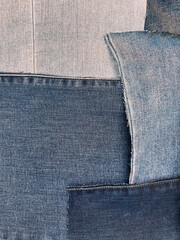 Pieces of material are arranged in attractive fashion as patchwork. The pieces are flat, ironed, clean and cut. Shapes are irregular and colors are muted tones of blue, from very light to deep navy.