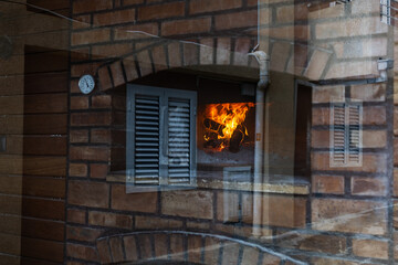 Fireplace glow seen through reflective window. Urban texture layers and warm flame create an...